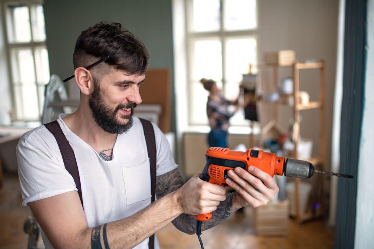 Ein Mann arbeitet mit einer Bohrmaschine in einem wohnlichen Raum.