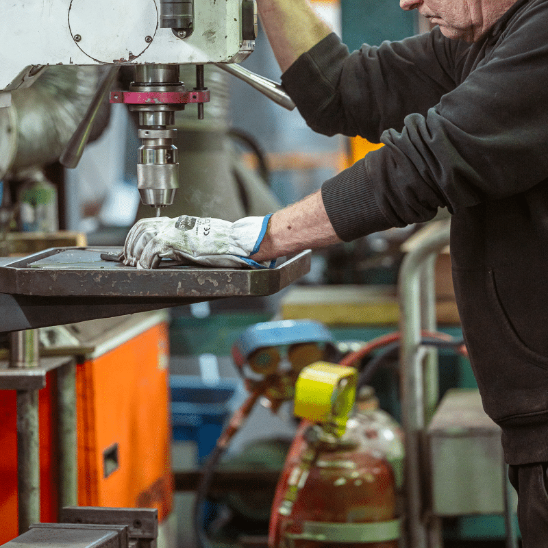 Ein Mitarbeiter bedient eine Maschine zur präzisen Metallbearbeitung in der Werkstatt.