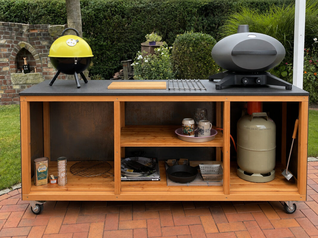 Mobile Outdoorküche mit Cortenstahl, Holzrahmen, Arbeitsplatte und zwei Grills im Garten stehend