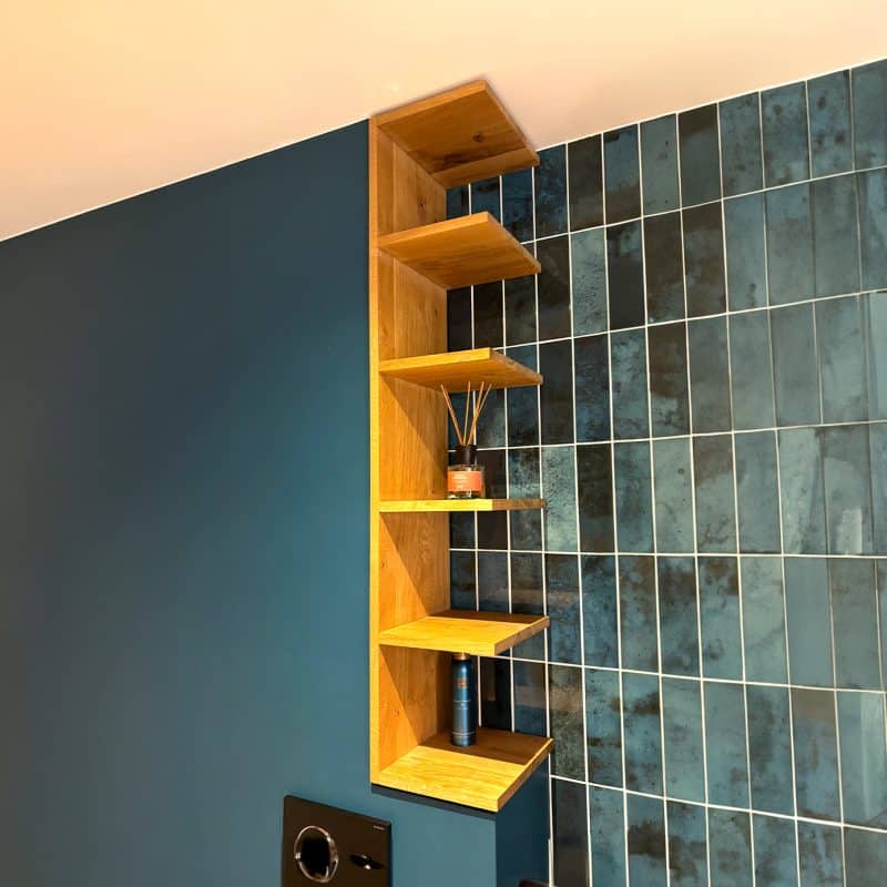 Ein Holzregal hängt an einer blauen Wand mit glänzenden Fliesen.