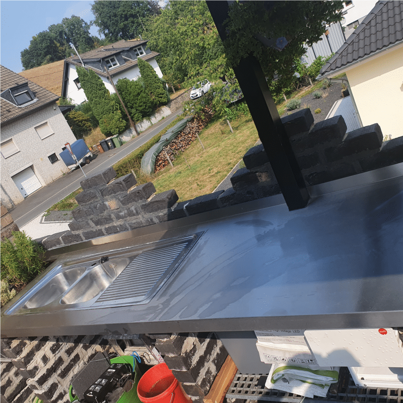 Eine Edelstahlküche ist passgenau auf einem Balkon integriert.