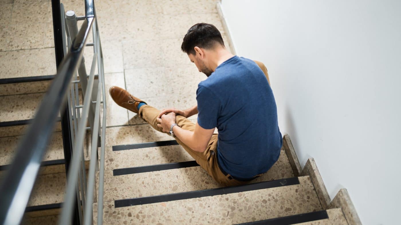 Eine Person sitzt im Innenbereich auf einer Treppenstufe.