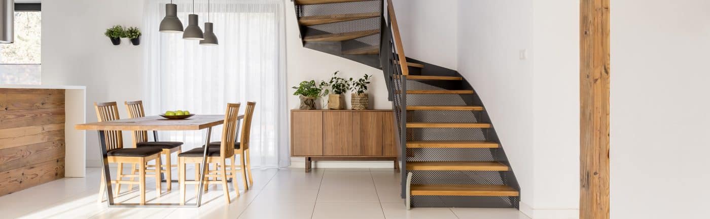 Eine offene Holztreppe verläuft über einem Sideboard mit Pflanzen.