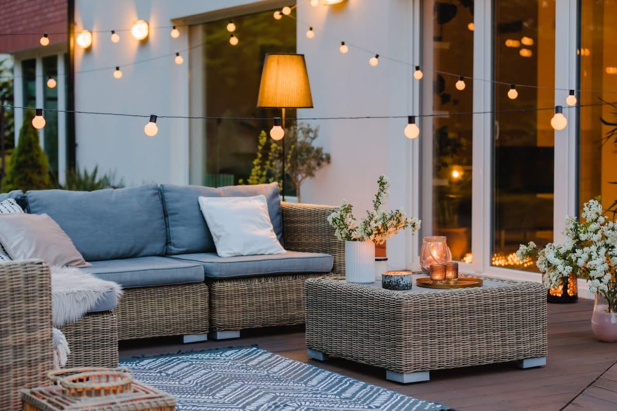 Moderne Terrassensitzgruppe mit Rattanmöbeln und stimmungsvoller Beleuchtung.