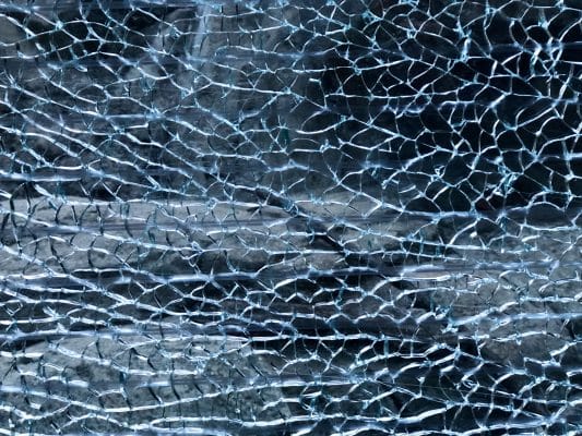 Eine rissige Glasoberfläche aus ESG-Glas zeigt feine Strukturen und Lichtreflexionen.
