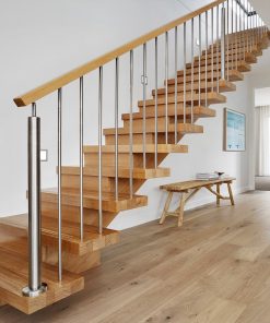 Eine moderne Holztreppe mit Edelstahlgeländer steht in einem hellen Wohnbereich.