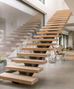 Eine moderne Holztreppe liegt zwischen weißen Wänden und führt zu einem Flur.
