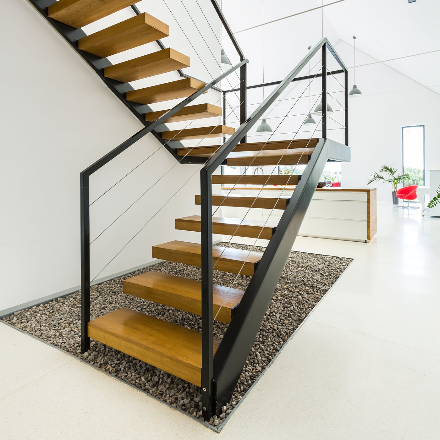 Das Bild zeigt eine moderne Stahltreppe mit Holzstufen in einem hellen Raum.