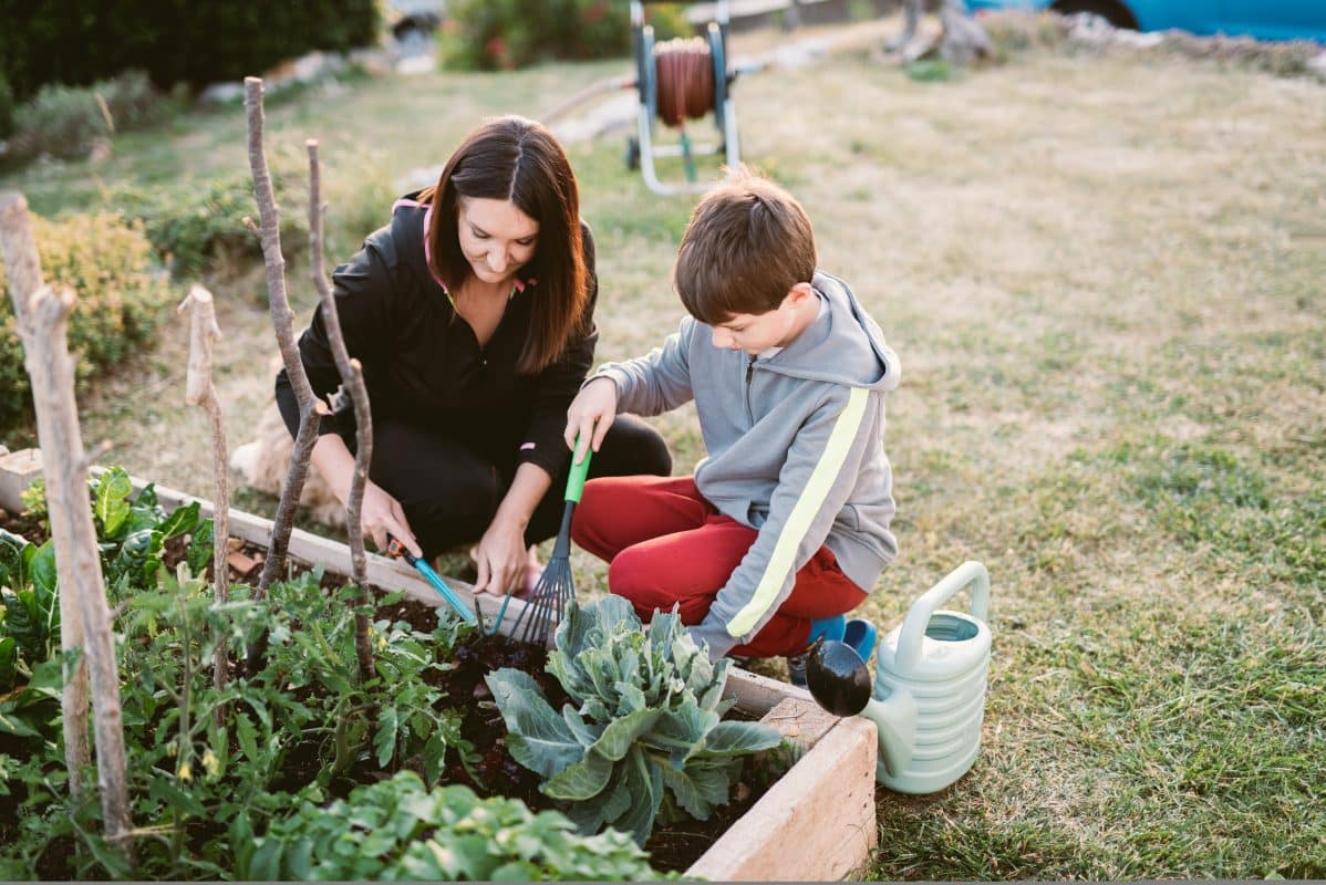 Mutter und Sohn gärtnern gemeinsam am Hochbeet - mit Gartenwerkzeug aus Schwarzstahl.