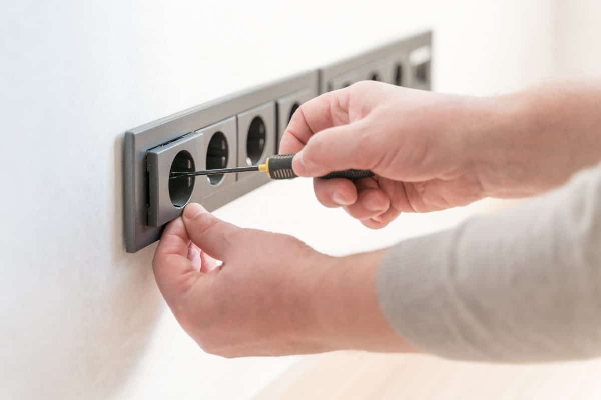 Handwerker schraubt an Mehrfachsteckdose.