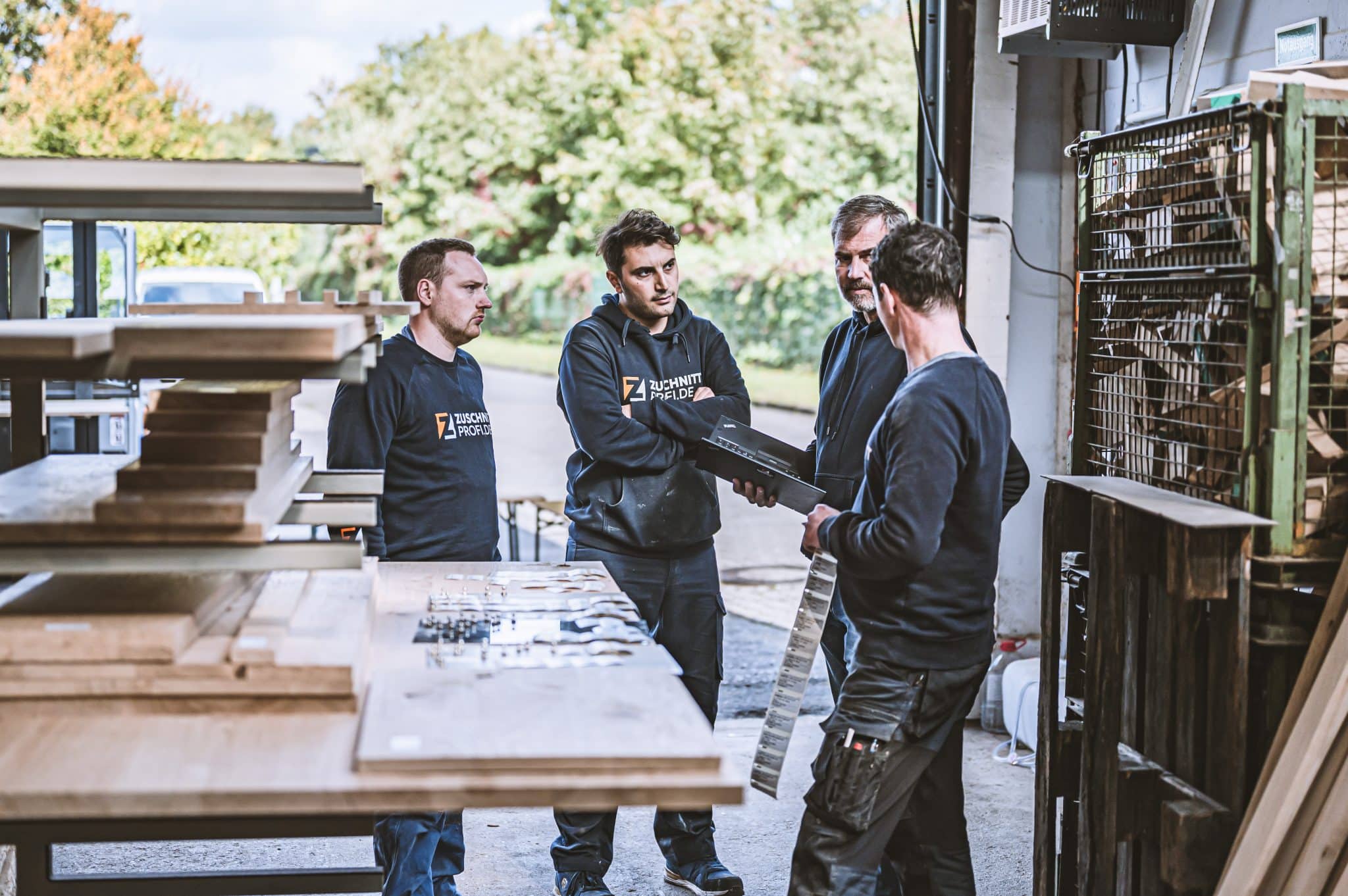 Das Team tauscht sich gemeinsam an einer Werkbank über ein Projekt aus.