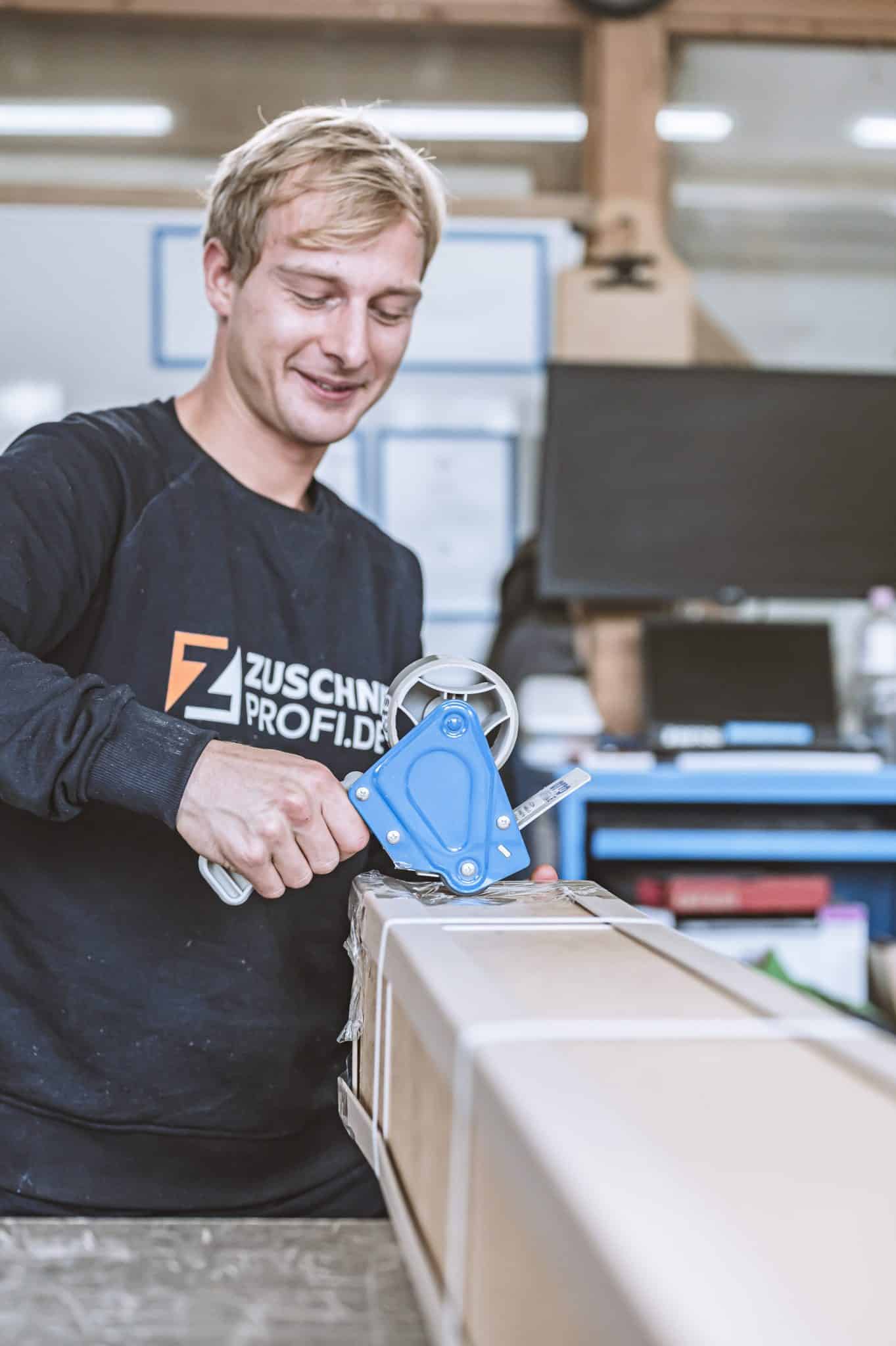Ein Mitarbeiter von zuschnittprofi.mom verpackt sorgfältig Materialien.