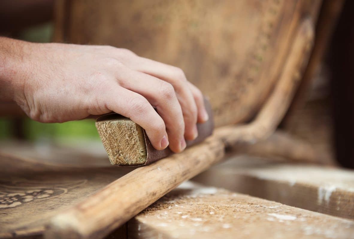 Hand schleift Holzstuhl mit Schleifklotz ab.